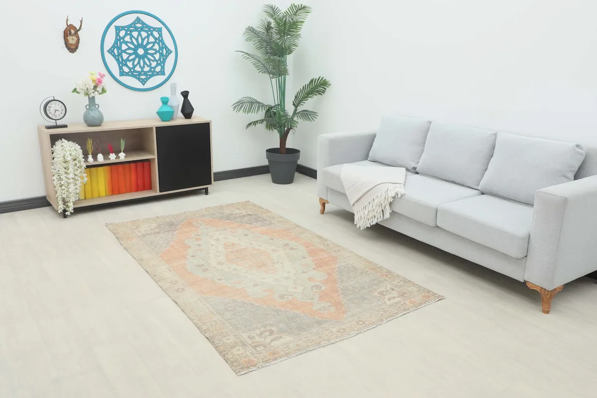 Vintage Anatolian rug with rust and gray medallion design in a modern living room setting.