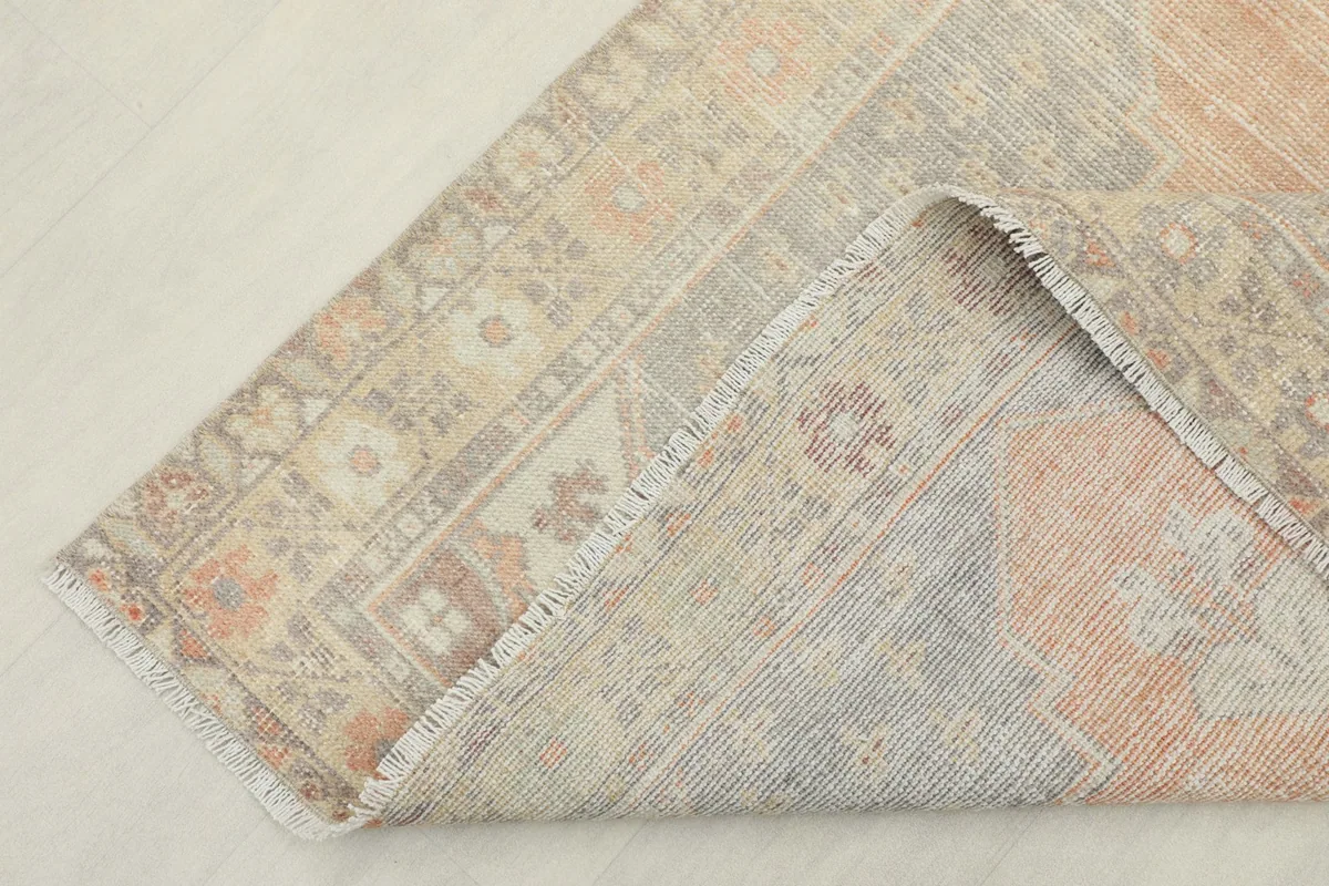 View of the rug's backside and folded edge, revealing the cotton foundation and knotting.