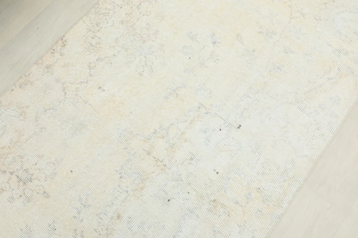 Detailed view of the rug's surface, revealing the low pile and intricate, faded wool patterns.
