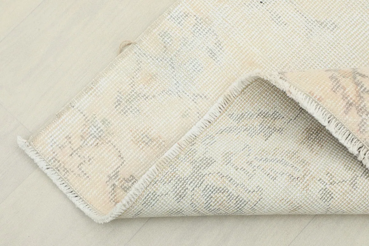 Corner of the rug folded back to display the cotton foundation and hand-knotted construction.