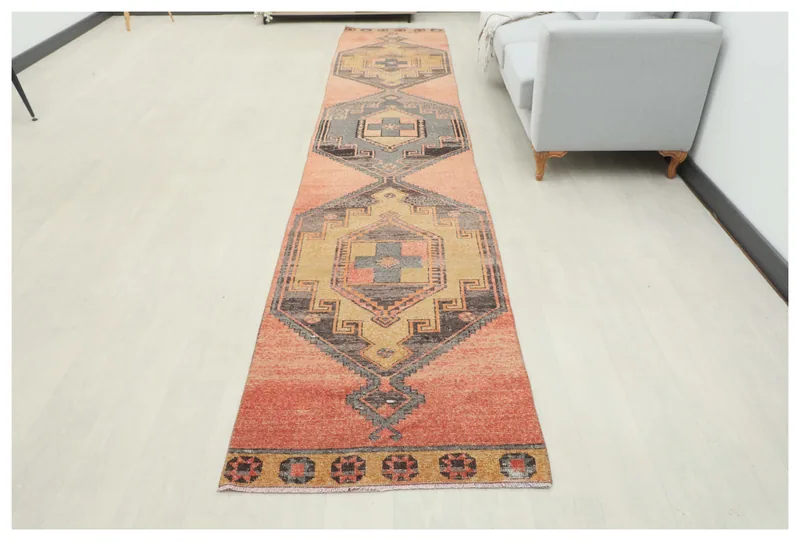Full top view of the 2'10" x 14'10" vintage Anatolian runner rug with geometric motifs on a rust field.