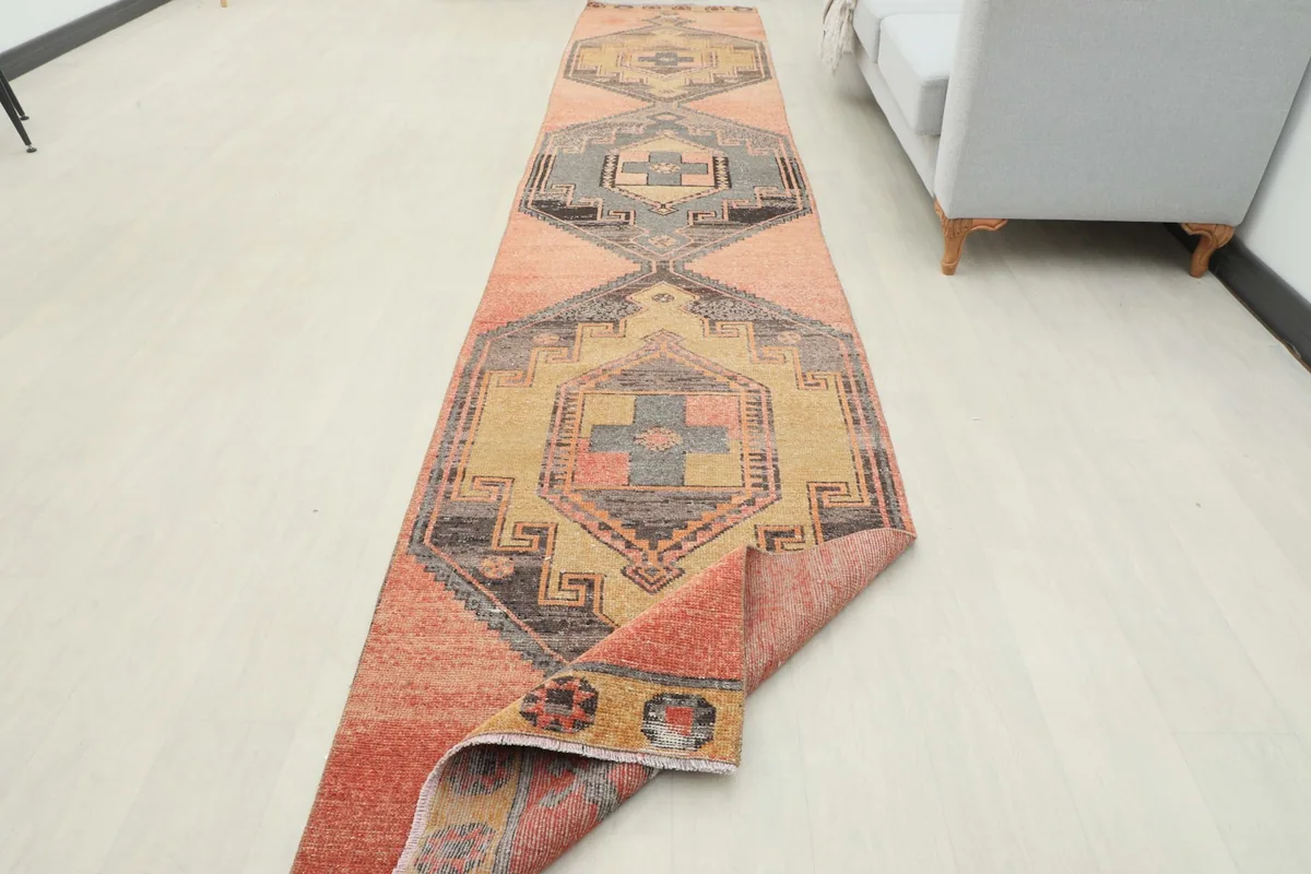 Partial view of the runner rug with one end folded, displaying the reverse side and colors.