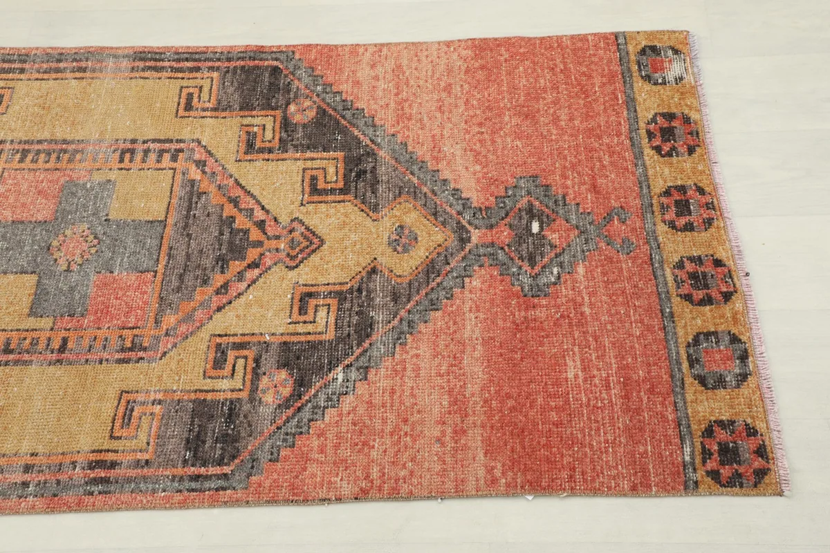 Close-up detail of the rust field and a tan, gray, and charcoal geometric motif on the runner.