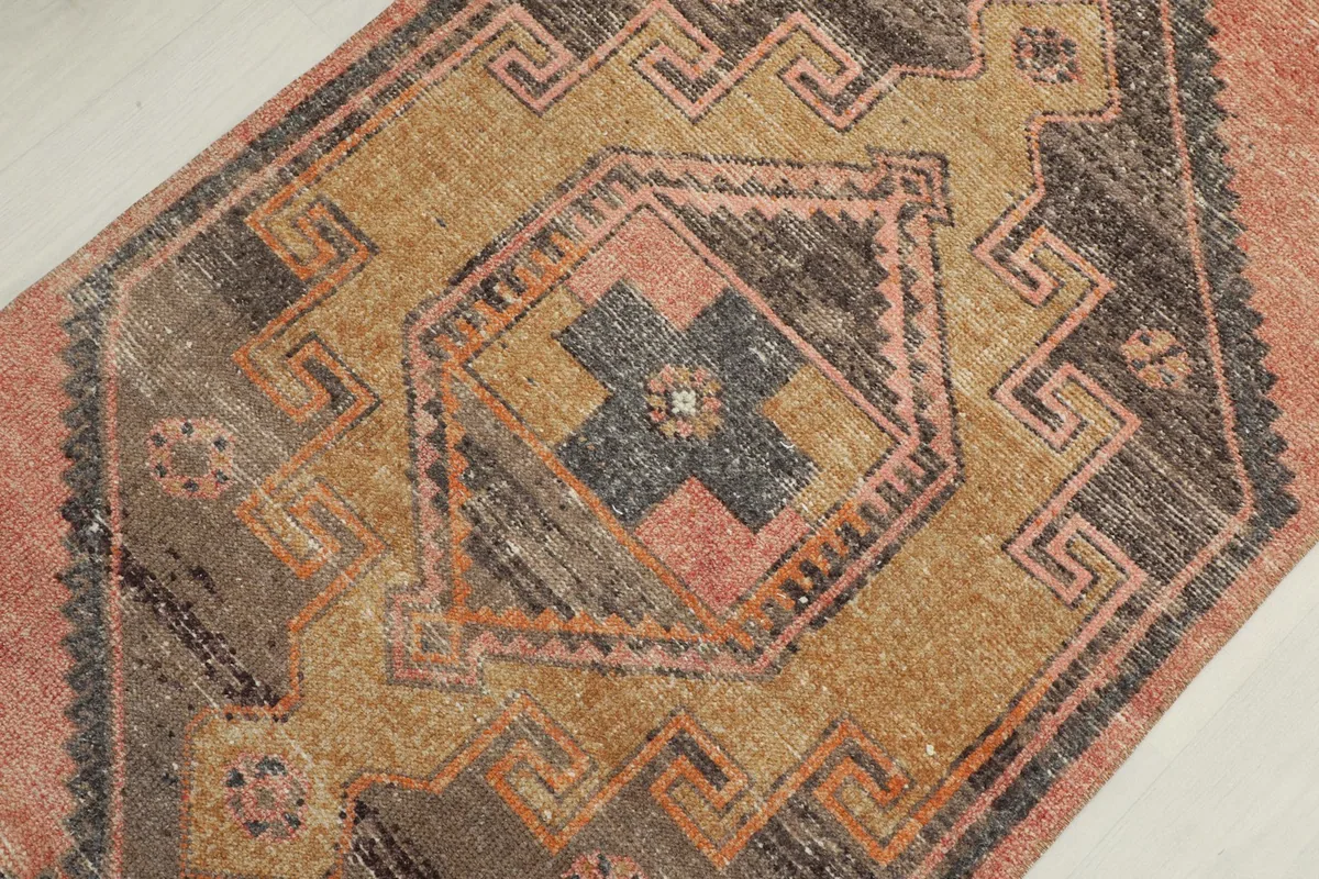 Close-up of a central geometric medallion with tan, gray, and rust colors, showcasing the knotting.
