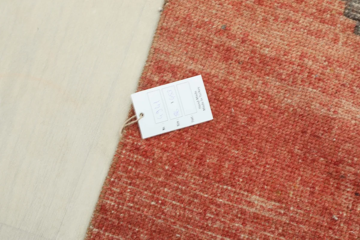 Close-up of the rug's label and the texture of the rust-colored wool pile.