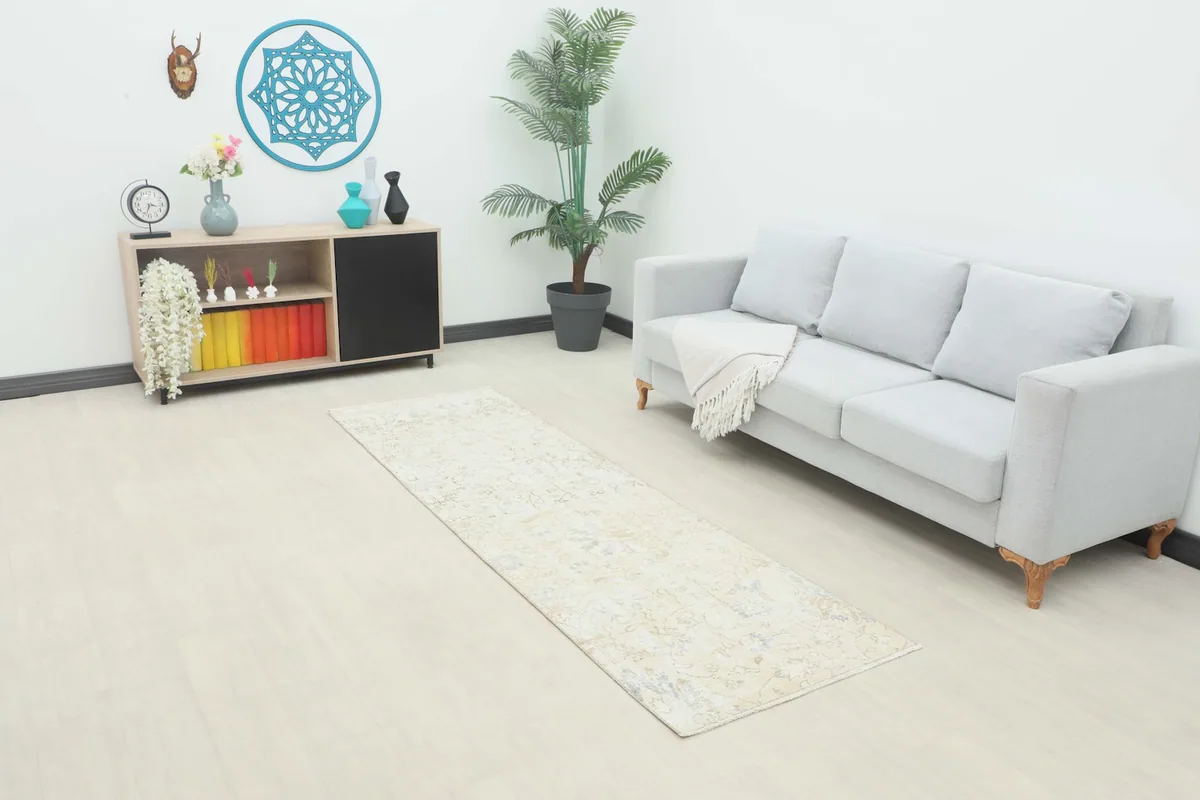 Beige runner rug in a modern living room setting with a light gray couch.
