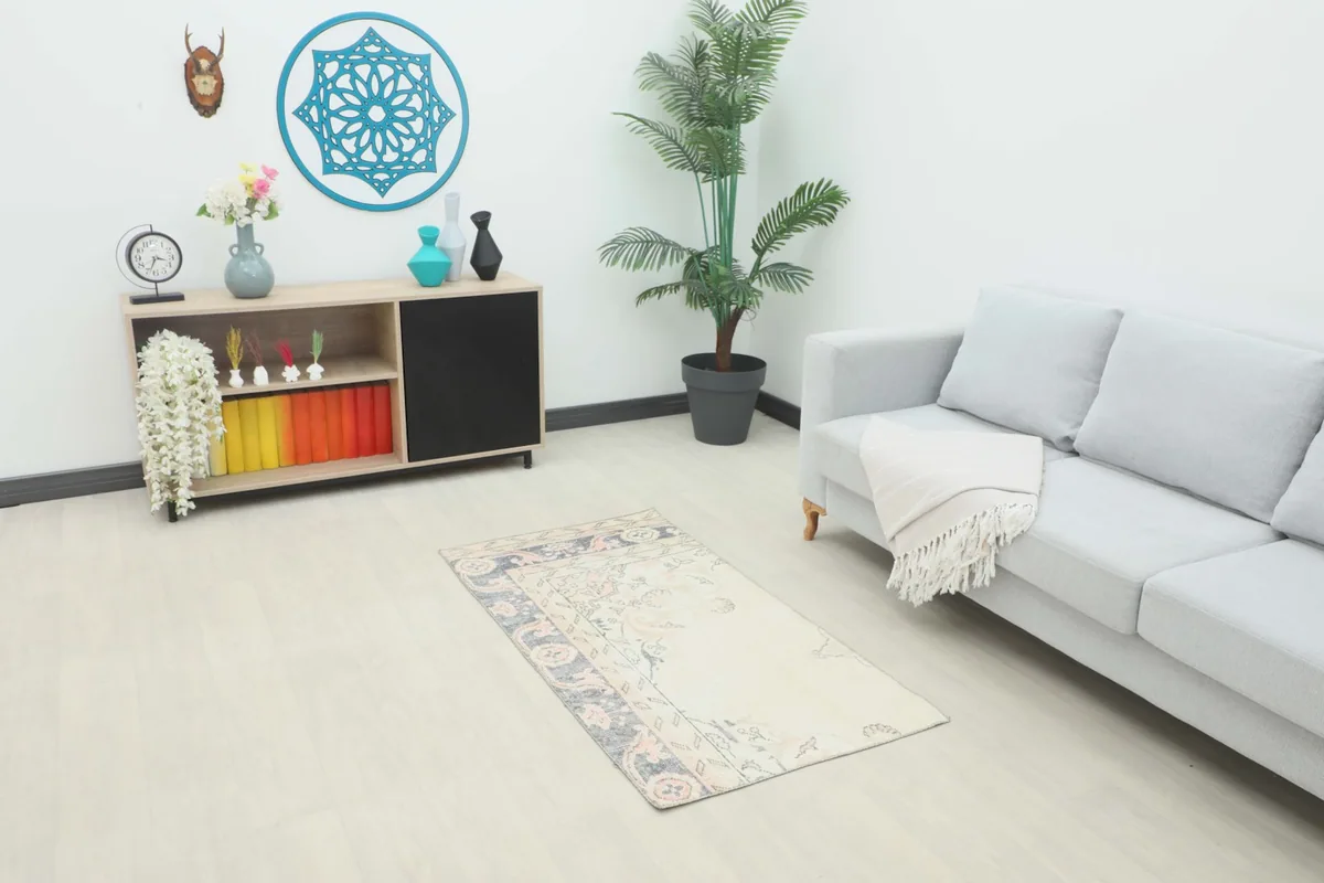 Ivory, navy, and rose vintage rug in a living room setting with a sofa and decor