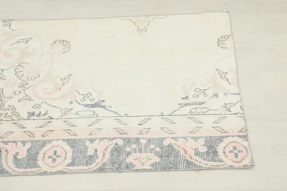 Close-up of the rug's ivory field with faded rose floral patterns and parts of the border