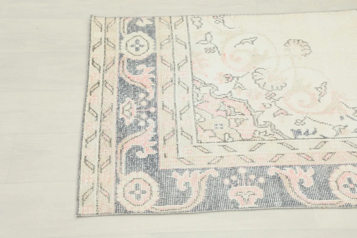 Detailed view of the navy border with rose and ivory geometric and scrolling motifs