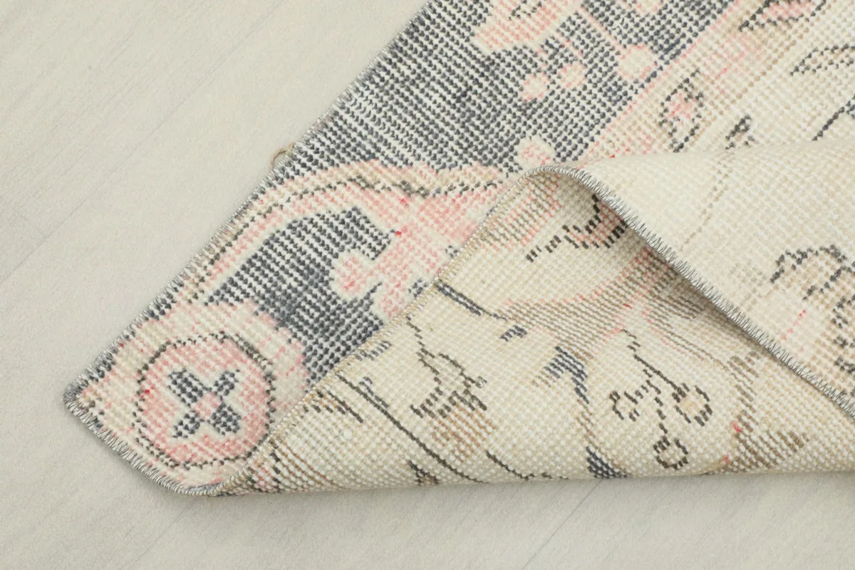 Corner of the rug folded to reveal the reverse side and the cotton foundation