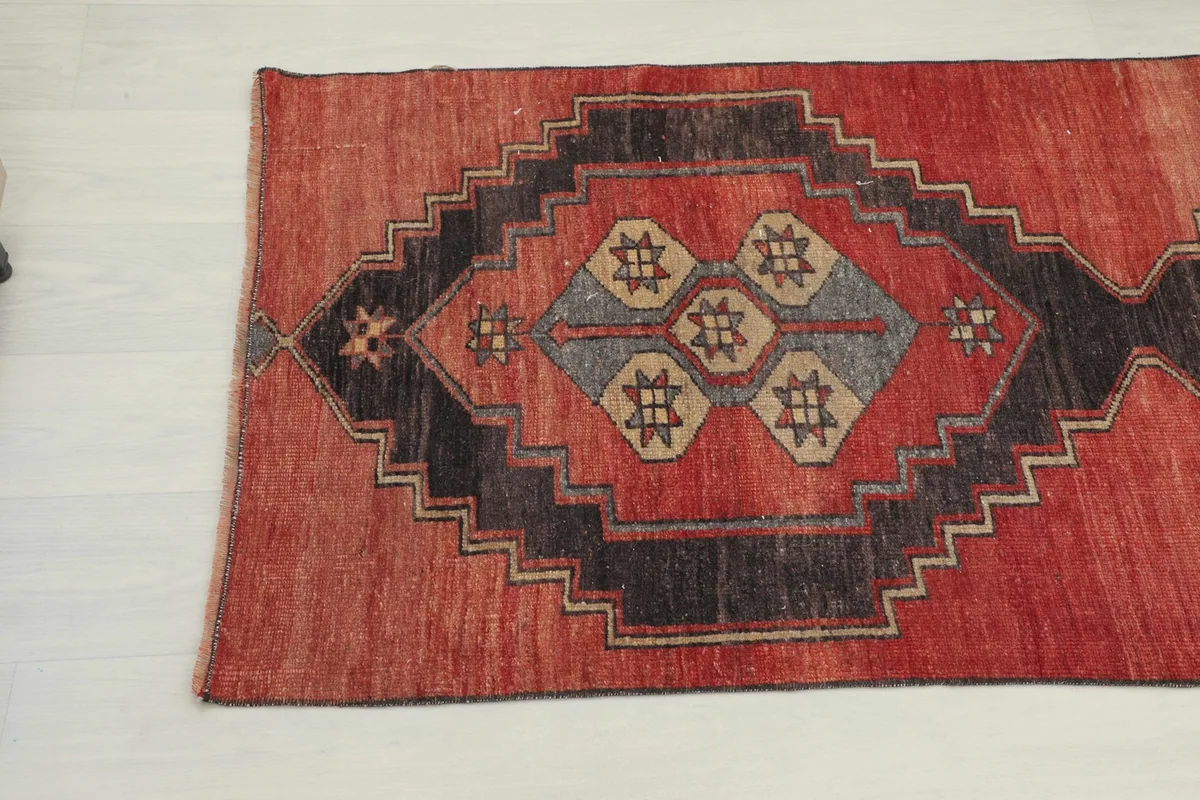 Overhead close-up of a geometric motif with rust, charcoal, gray, and tan colors.