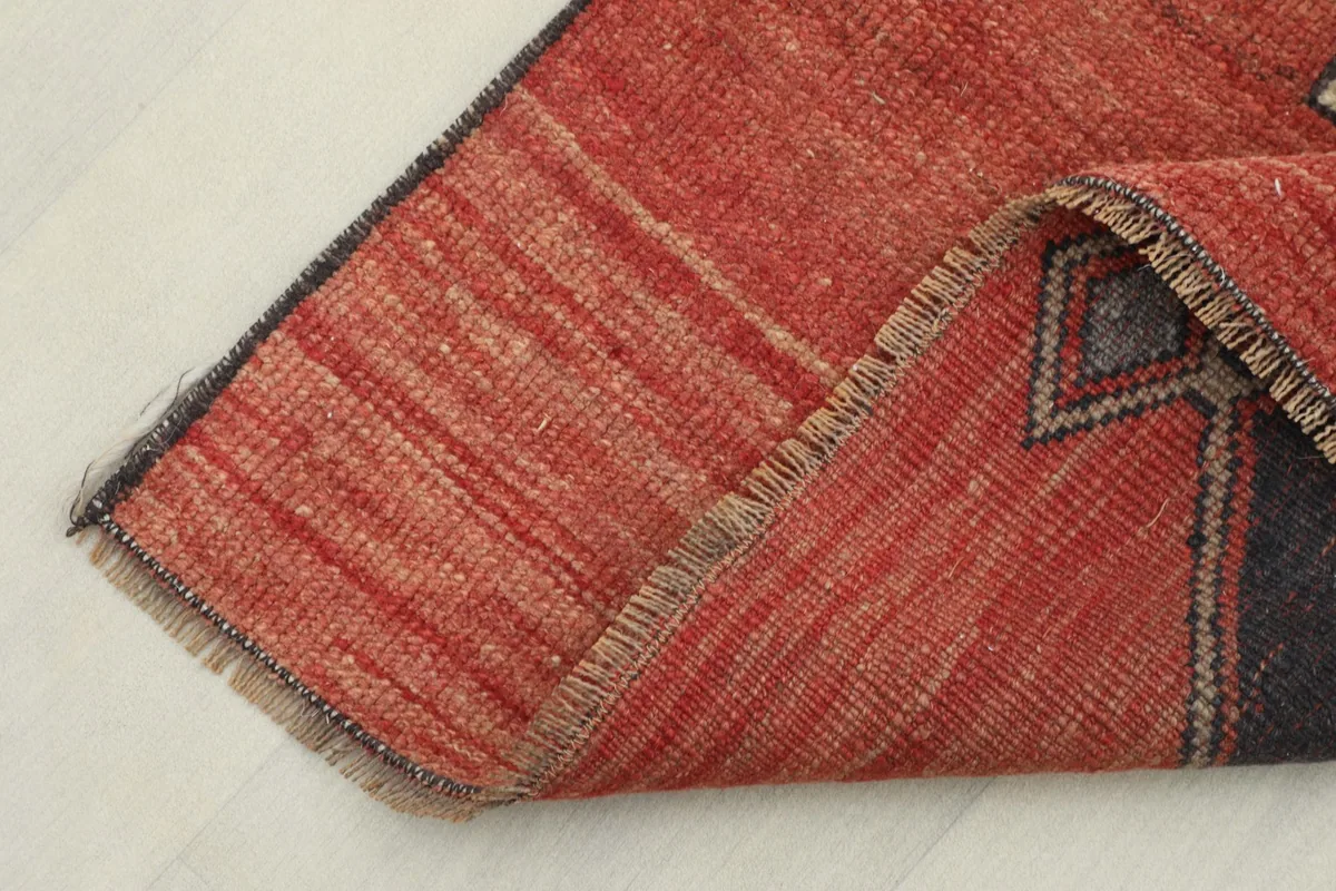 Folded edge of the rug showing the low wool pile and the hand-knotted texture.