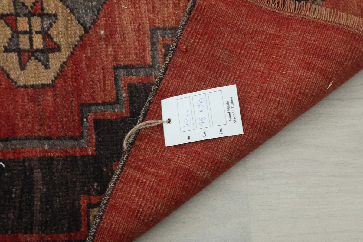View of the rug's back with a tag, showing the cotton foundation and hand-knotted structure.