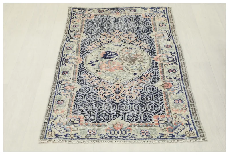 Full top view of the vintage navy, beige, and pink Anatolian area rug on a white background.