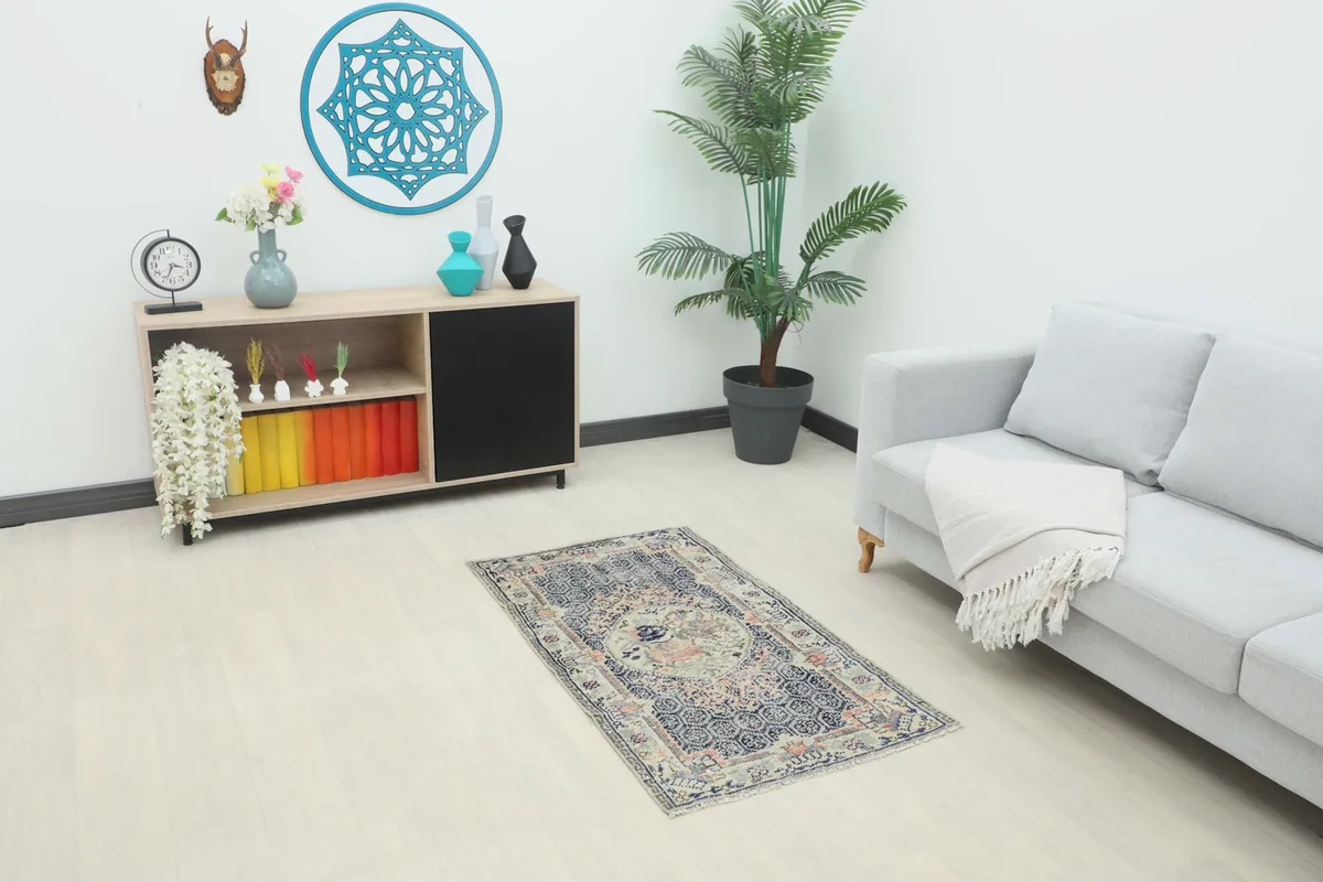 Vintage Anatolian rug displayed in a living room setting with a light sofa and side cabinet.