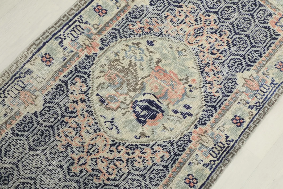 Close-up of the central floral medallion with navy, beige, and pink motifs.