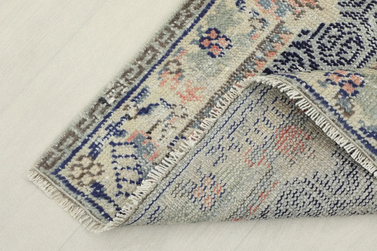 View of the rug's underside and folded corner, showing the cotton foundation and construction.