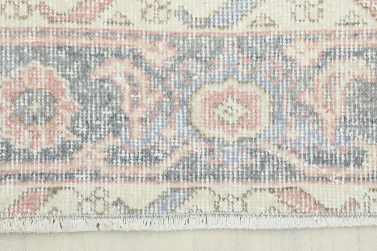 Close-up detail of the runner's border, featuring intricate blue, pink, and ivory patterns.