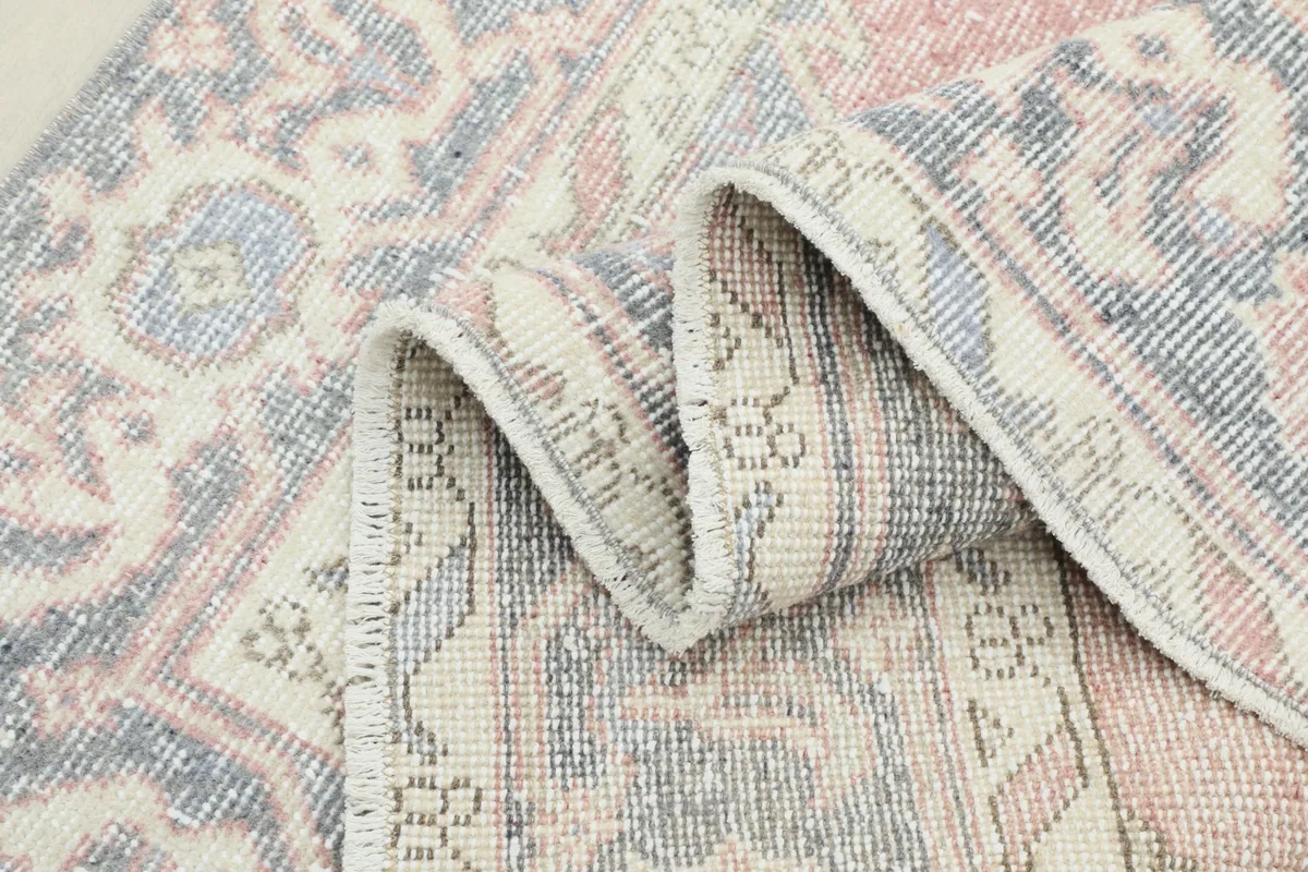 Close-up of the rug's low pile and texture, showing the vintage wear and soft color blend.