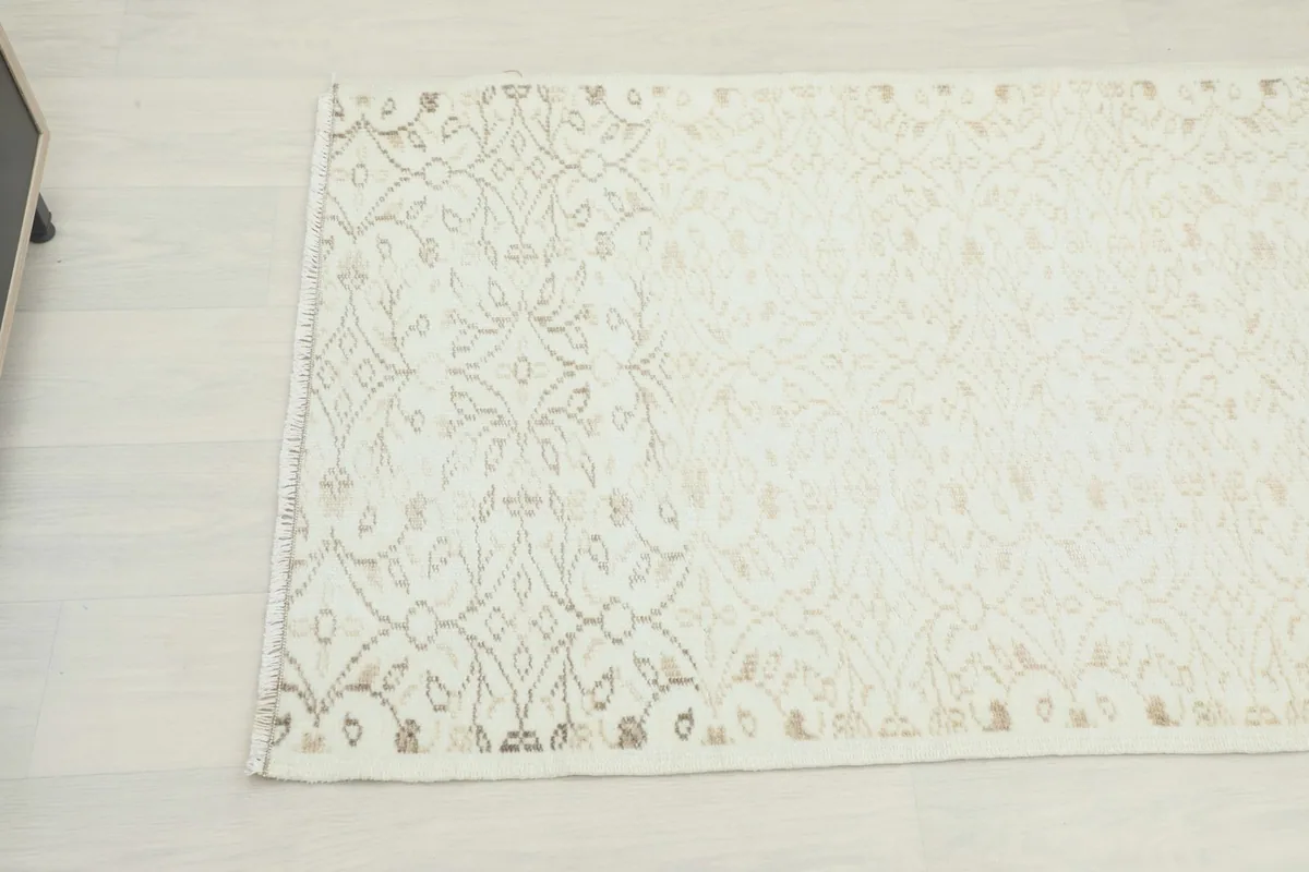 Close-up overhead view of the rug's cream field with subtle tan geometric patterns.