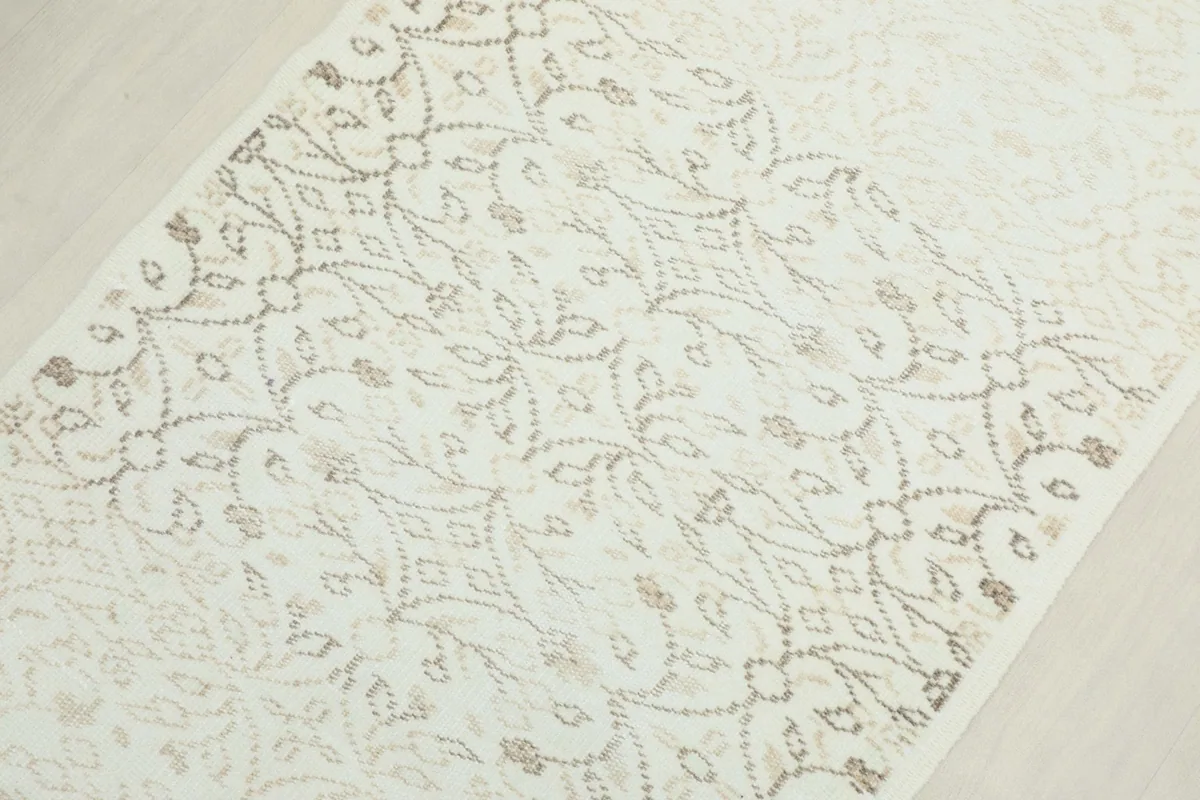 Detailed view of the intricate tan geometric motifs on the cream background of the runner.