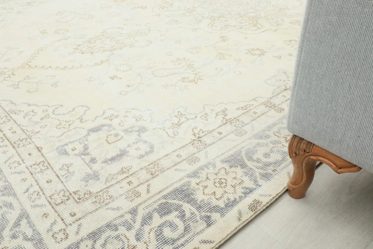 Corner of the ivory gray rug next to a sofa leg, showing its integration into a living space.