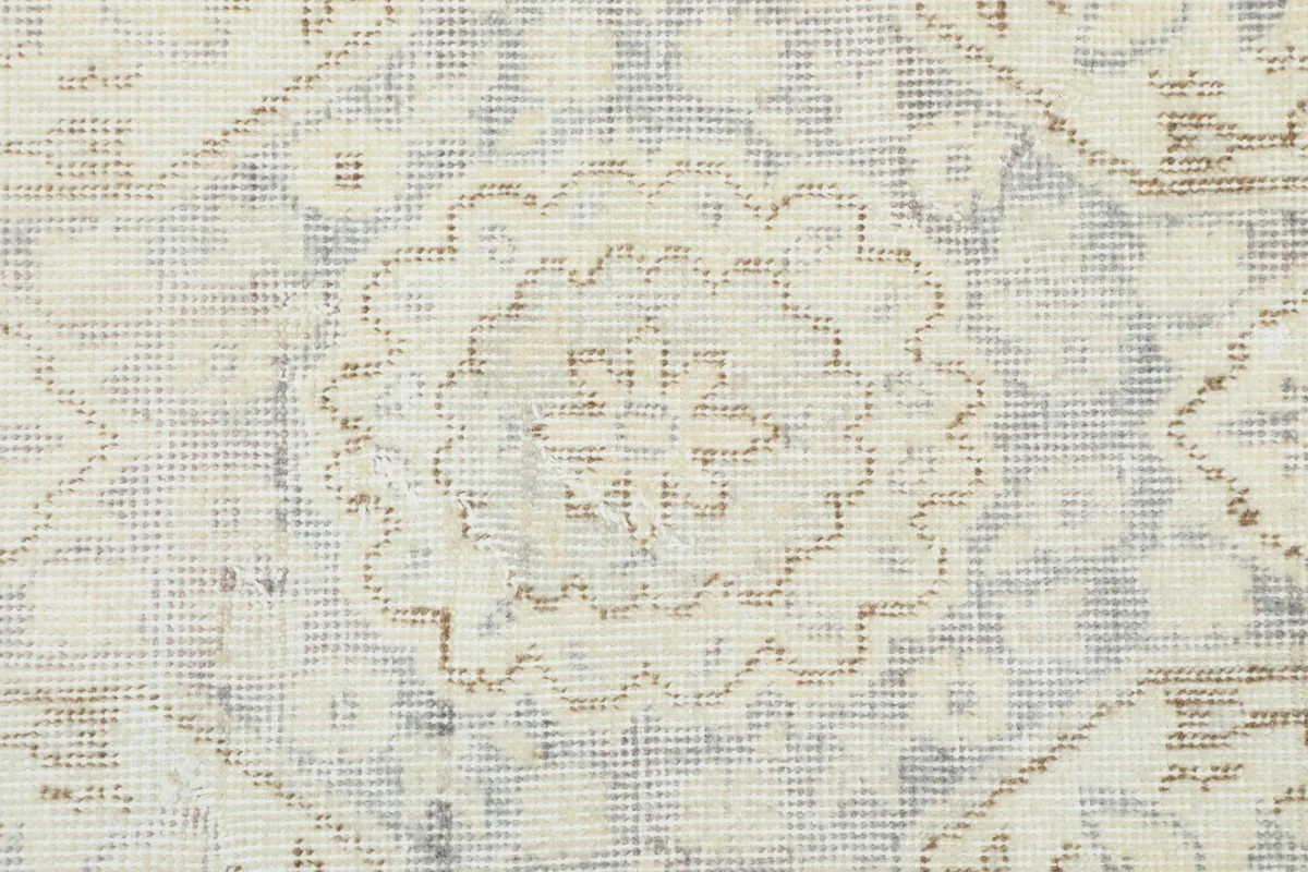 Macro detail of the hand-knotted wool pile, revealing the texture and faded gray and beige threads.