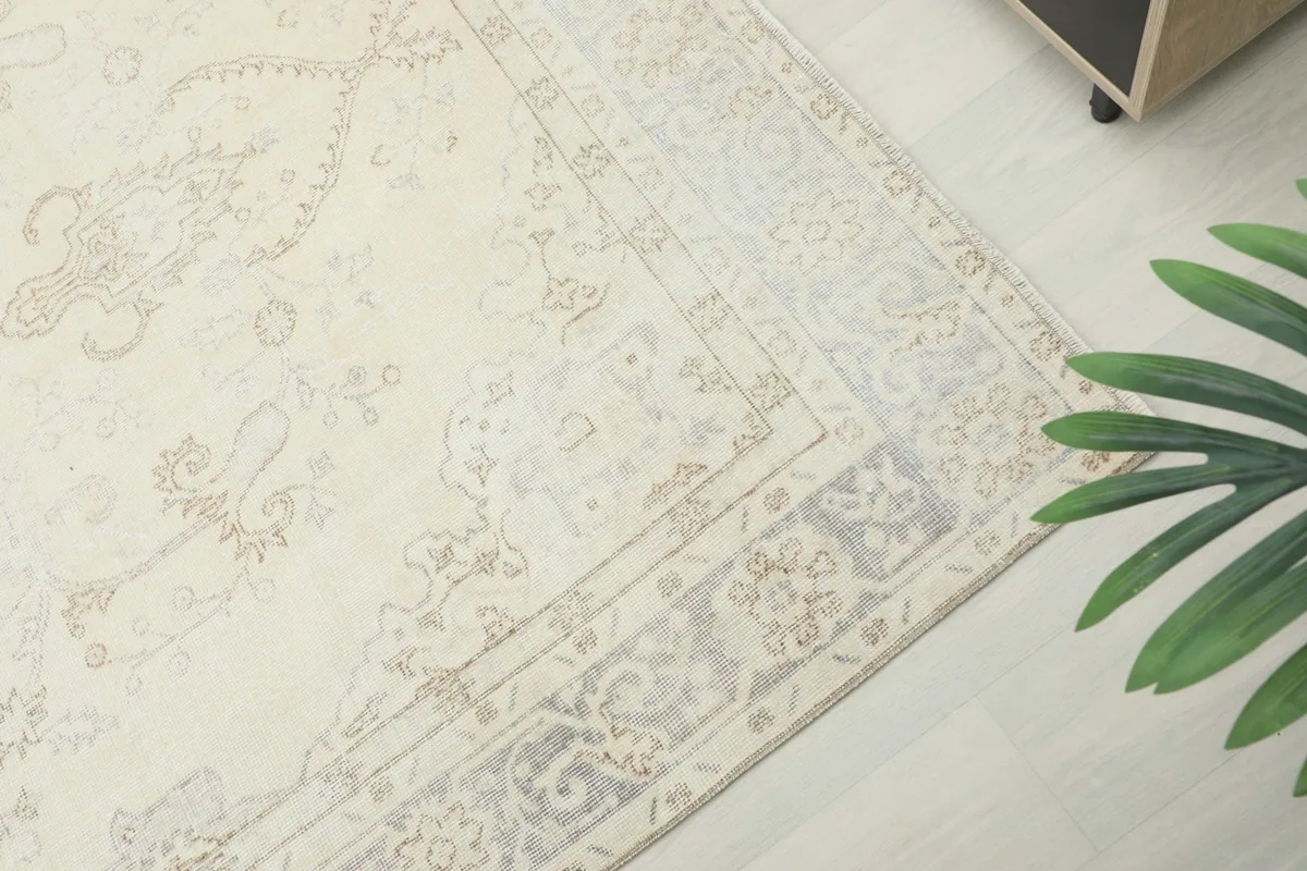Close-up of the rug's outer border, showing the intricate gray and beige motifs and low pile.