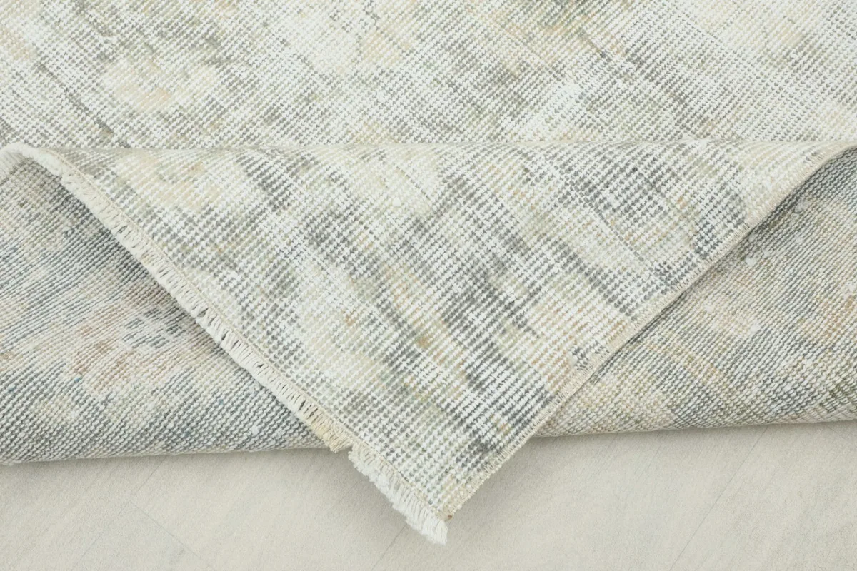 Folded corner of the rug revealing the cotton foundation and the back of the hand-knotted wool pile.