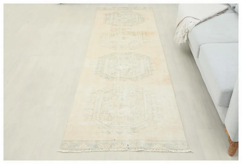 Full top view of the beige and blue geometric vintage runner rug on a white floor