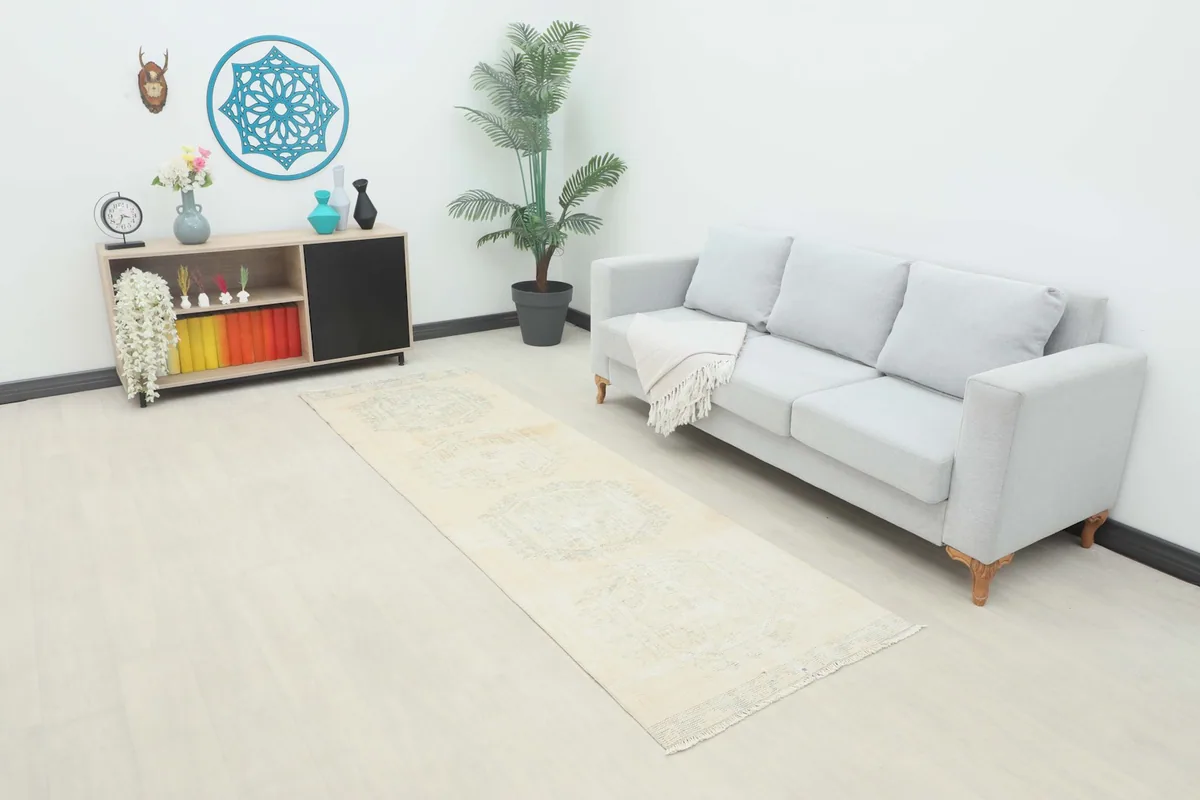 Vintage runner rug in a room setting, showing its length beside a light gray sofa