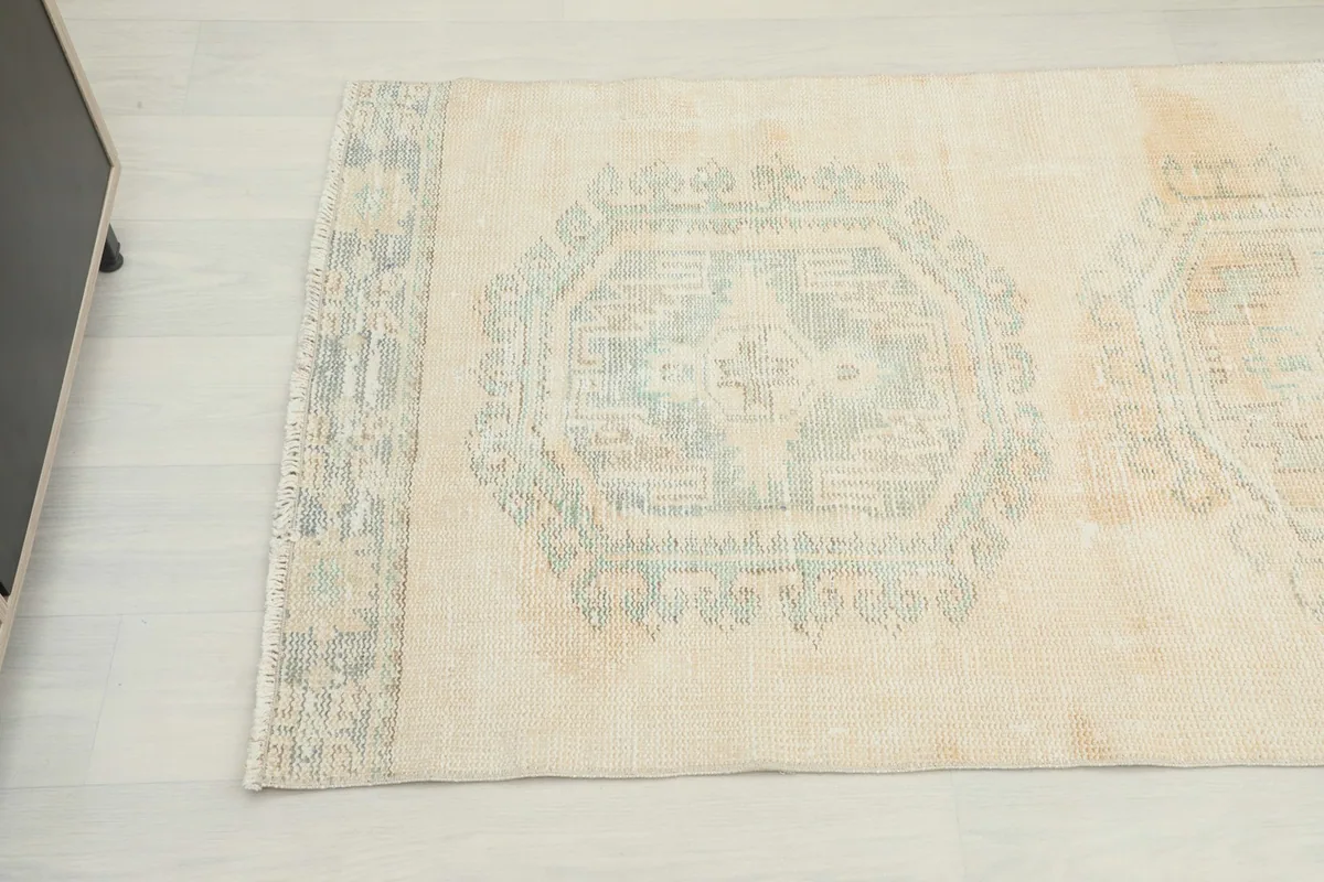 Detailed view of one geometric medallion motif in faded blue on the beige field