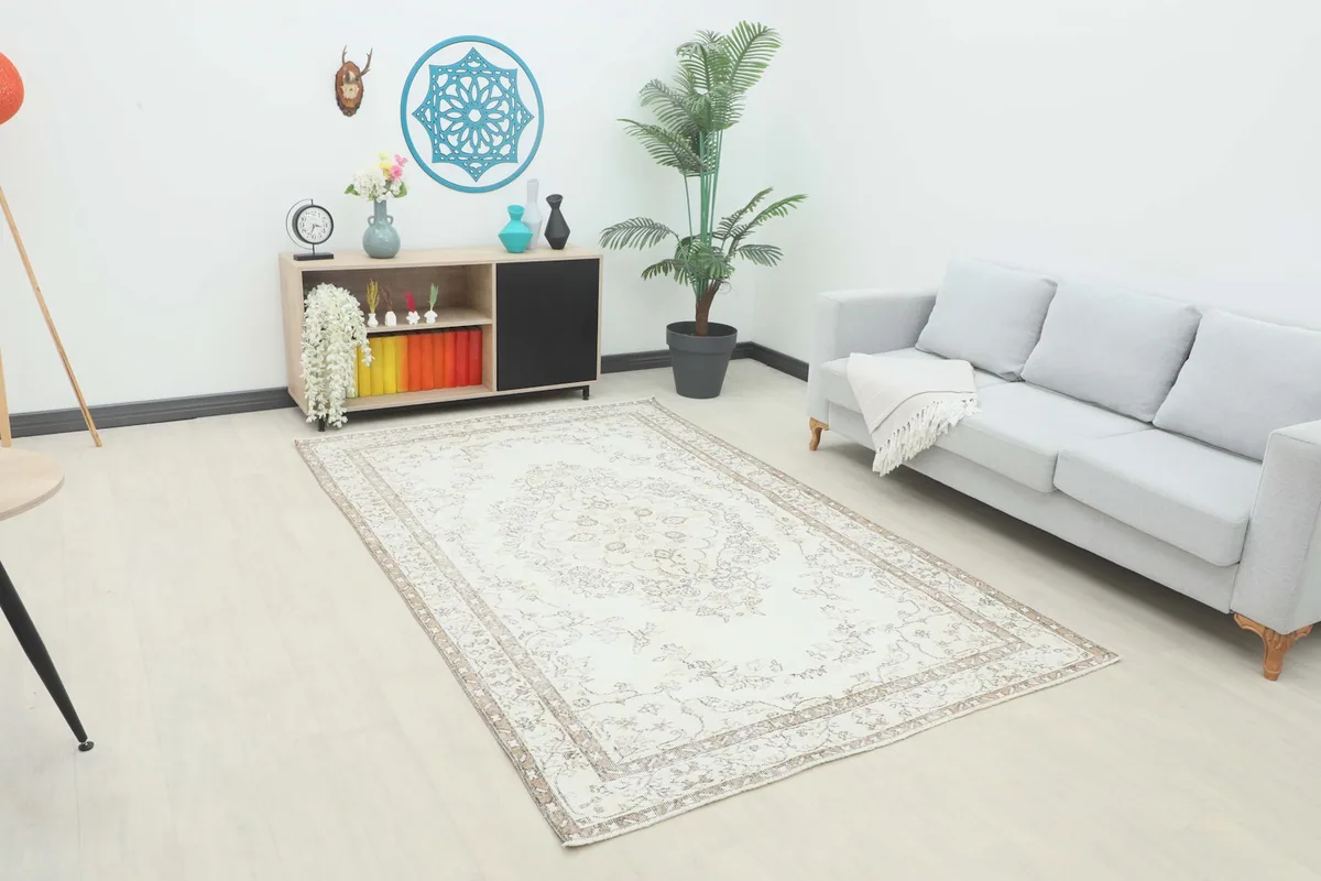 Ivory and brown vintage rug placed in a modern living room setting with a light gray sofa.
