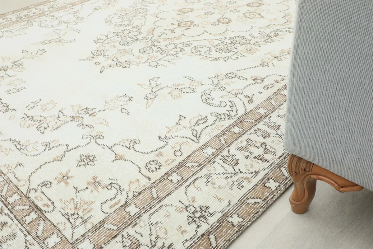 View of the rug next to a sofa leg, illustrating its placement and the subtle colors.