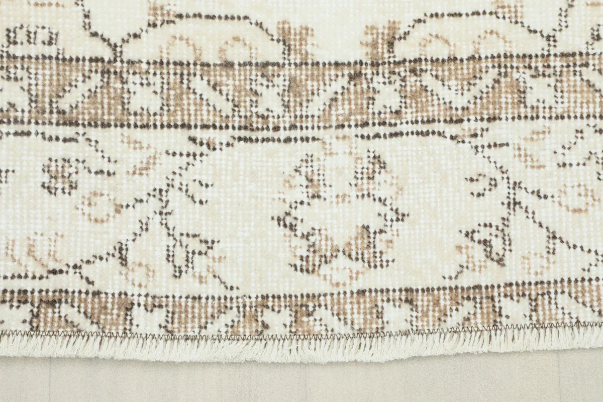 Close-up view of the rug's border showing intricate brown and tan geometric patterns.