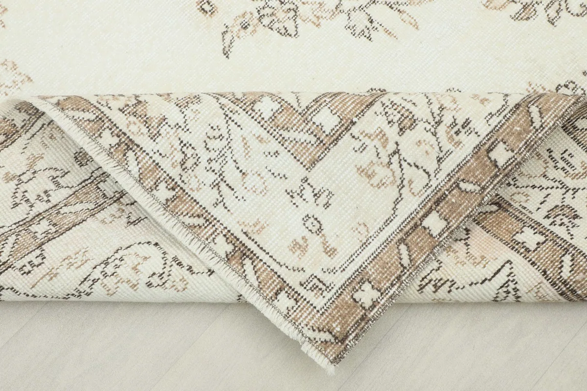 Corner of the rug folded back, revealing the reverse side and the hand-knotted construction.