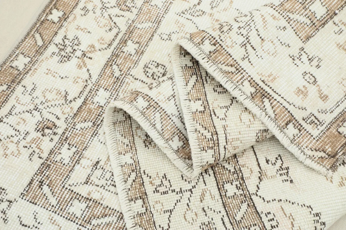 Rug partially folded, showcasing the texture of the wool pile and the border design.