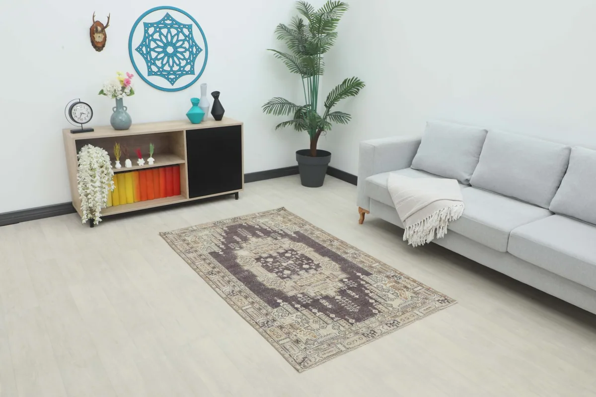 Vintage Anatolian rug placed in a modern living room setting with a gray sofa and wooden cabinet.
