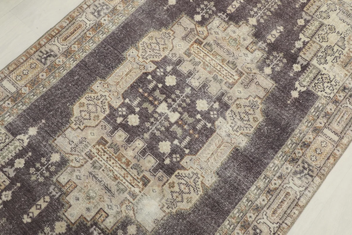 Overhead close-up of the central medallion and surrounding geometric motifs on the charcoal rug.
