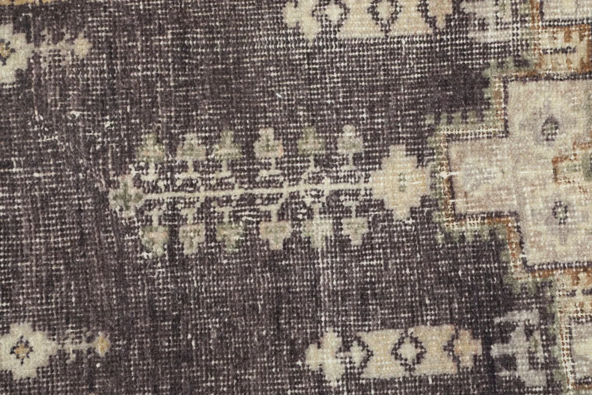 Extreme close-up showing the low pile and texture of the hand-knotted wool rug, revealing wear.