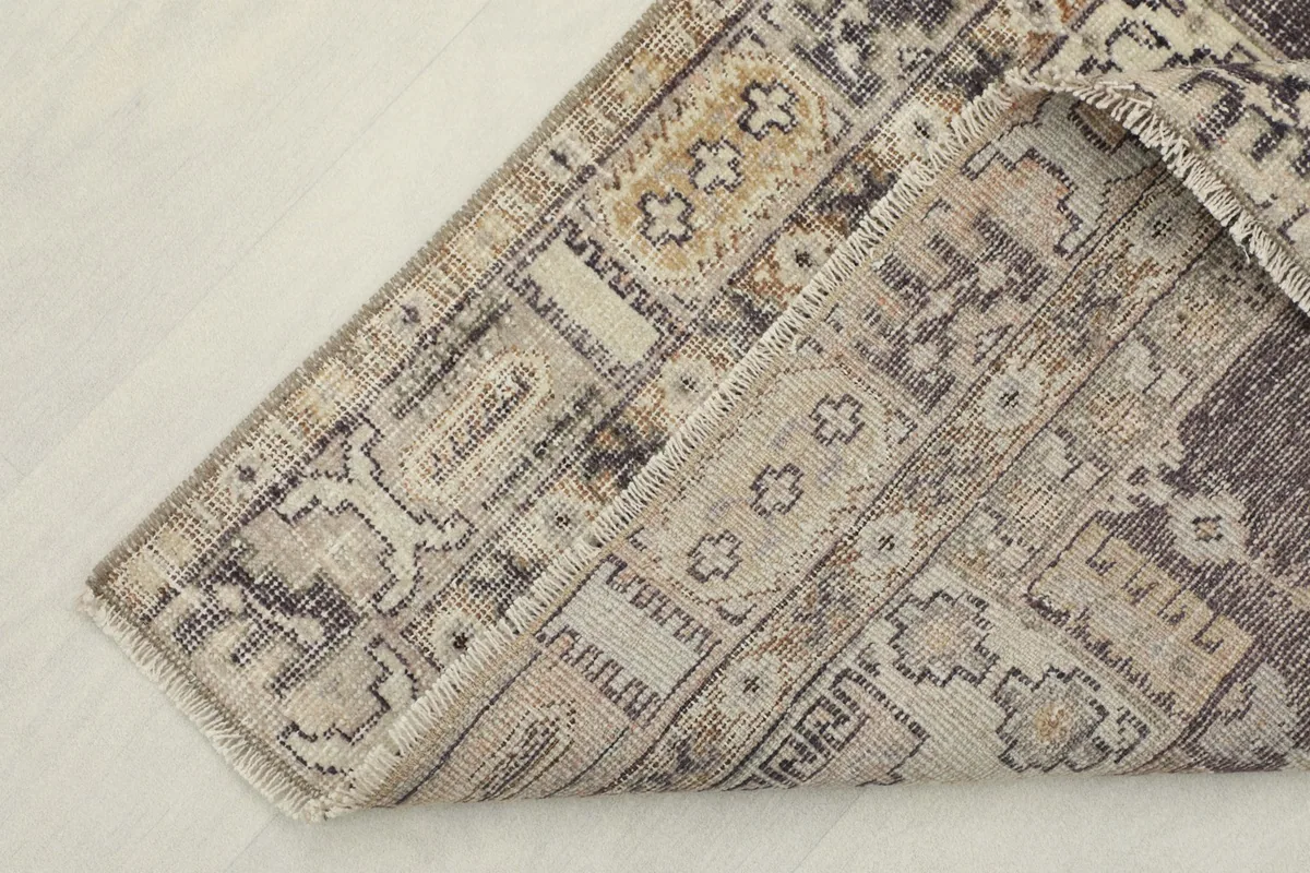 View of the underside of a corner of the rug, showing the cotton foundation and hand-knotted construction.