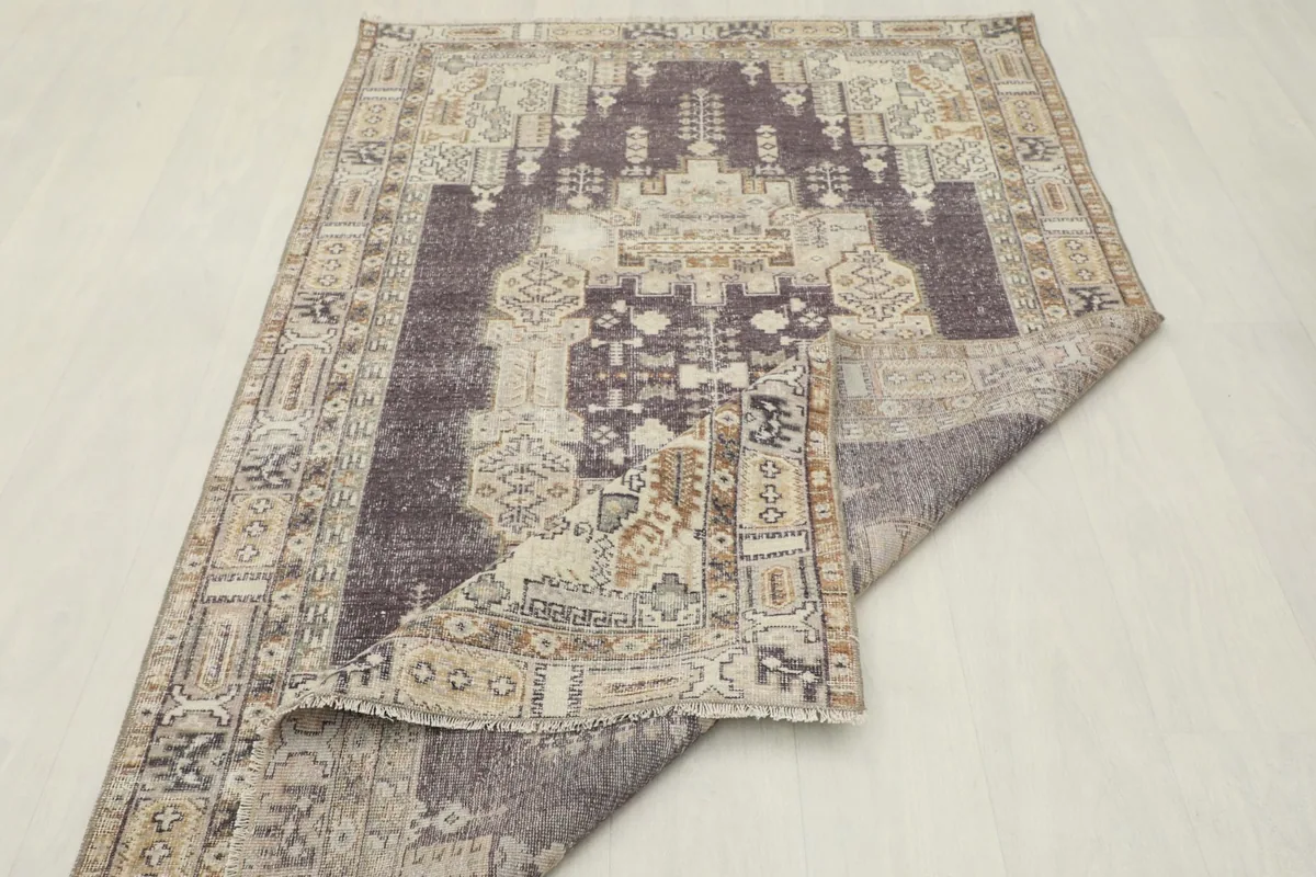 Rug partially folded, displaying the back of the rug and the reverse side of the patterns.