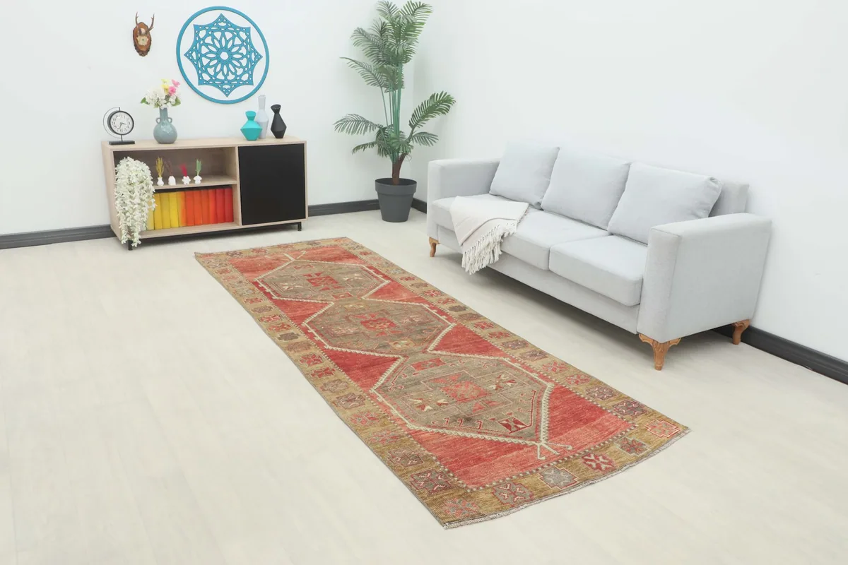 Long view of the red and tan runner rug in a room setting with a sofa and console