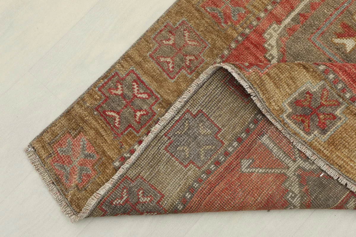 Corner of the runner rug folded back, showing the reverse side and fringe detail