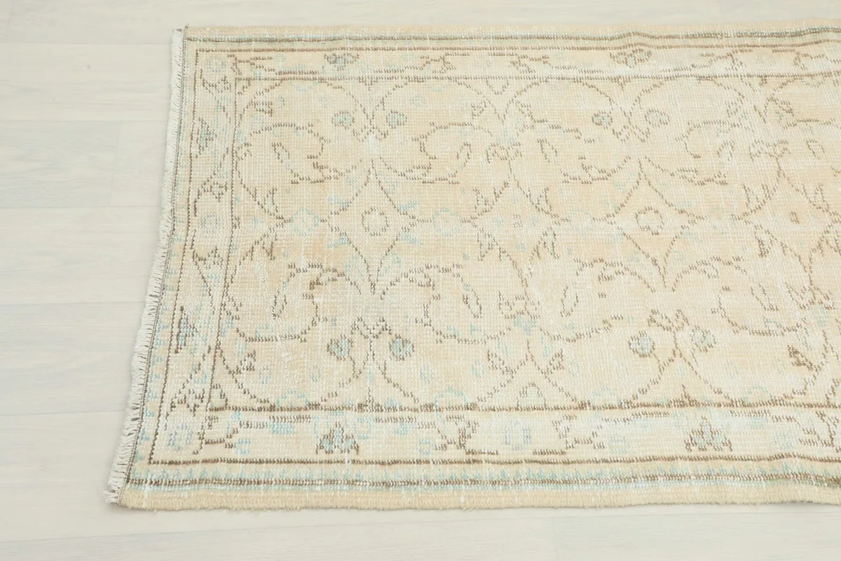 Angled view focusing on the other end of the cream runner rug, highlighting the subtle patterns.