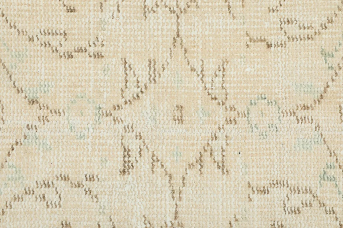 Close-up detail of the hand-knotted pile and the faded brown and blue geometric design elements.