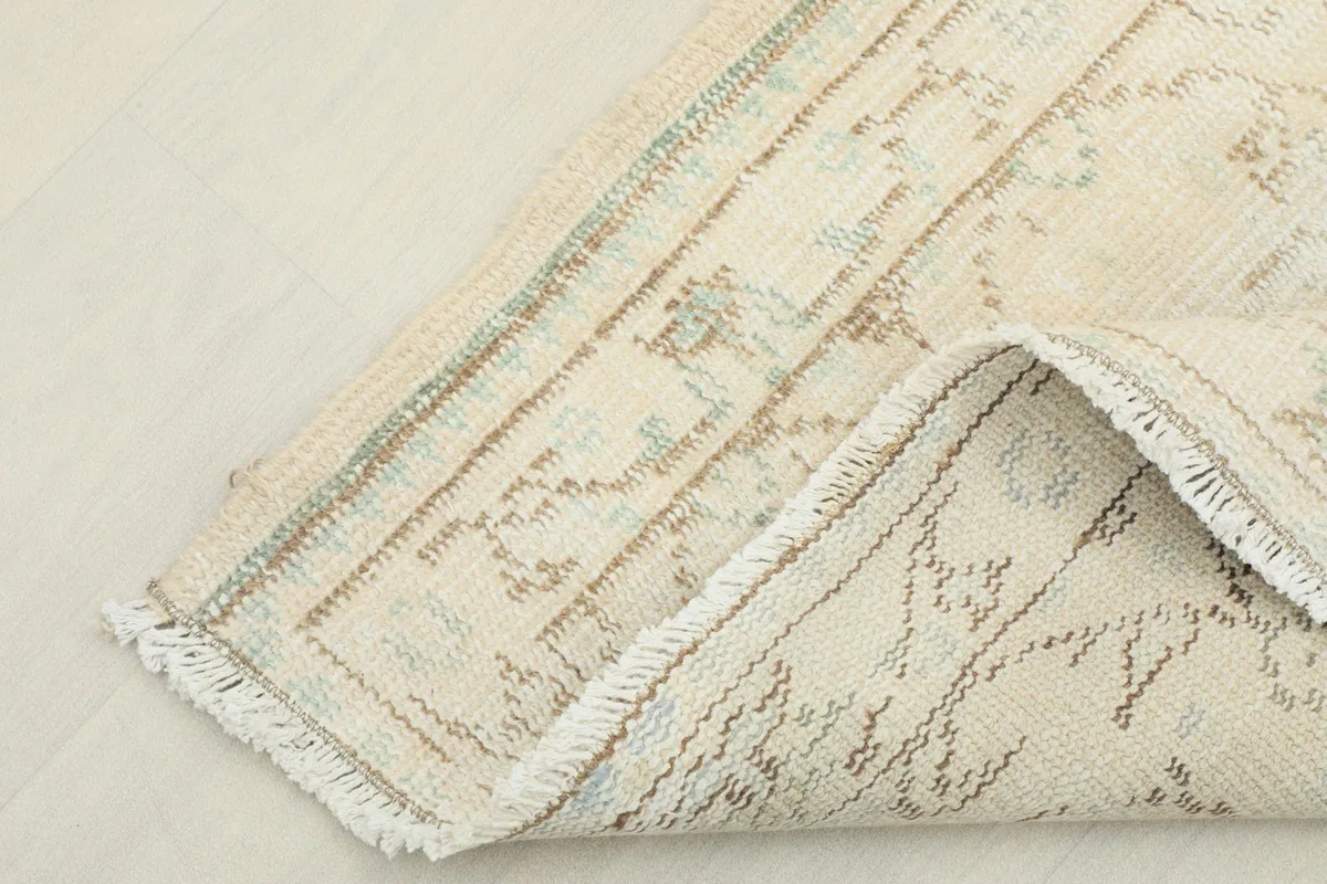 Detail of the reverse side of the hand-knotted cream runner rug, showcasing the cotton foundation.