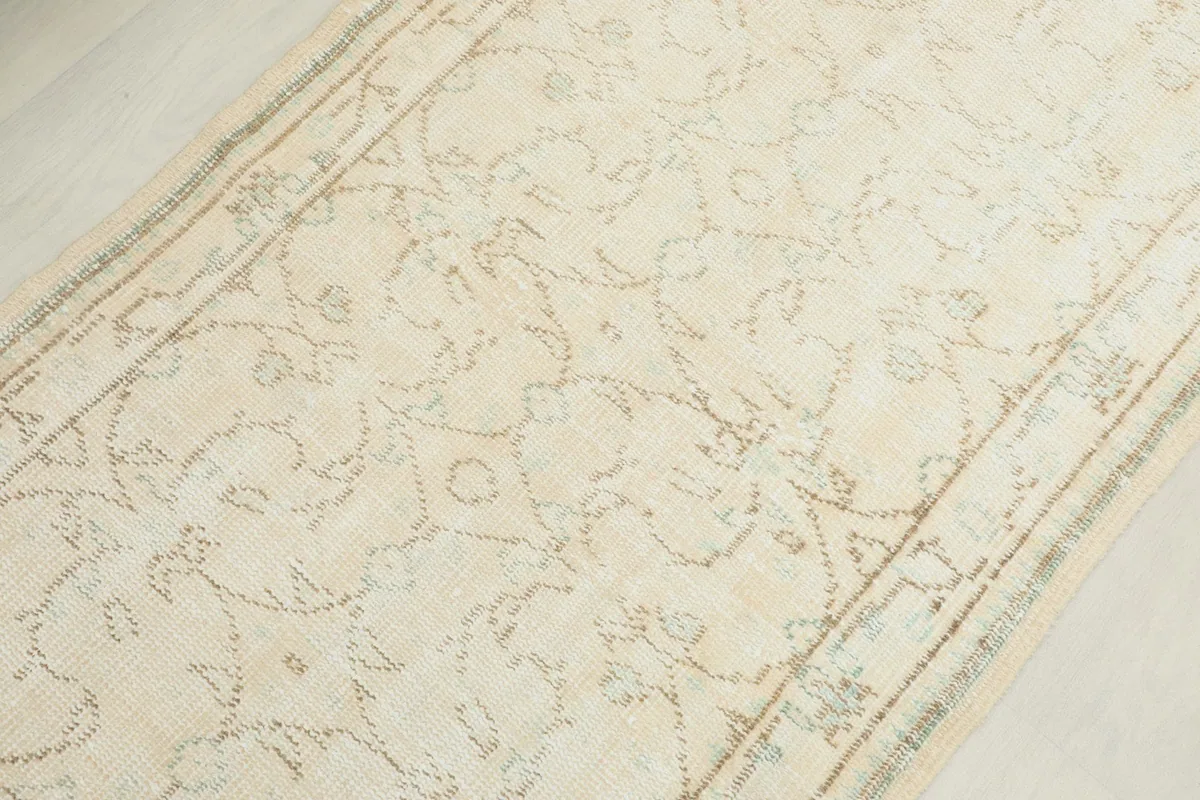 Overhead view of a section of the cream runner rug, revealing the detailed geometric motifs.