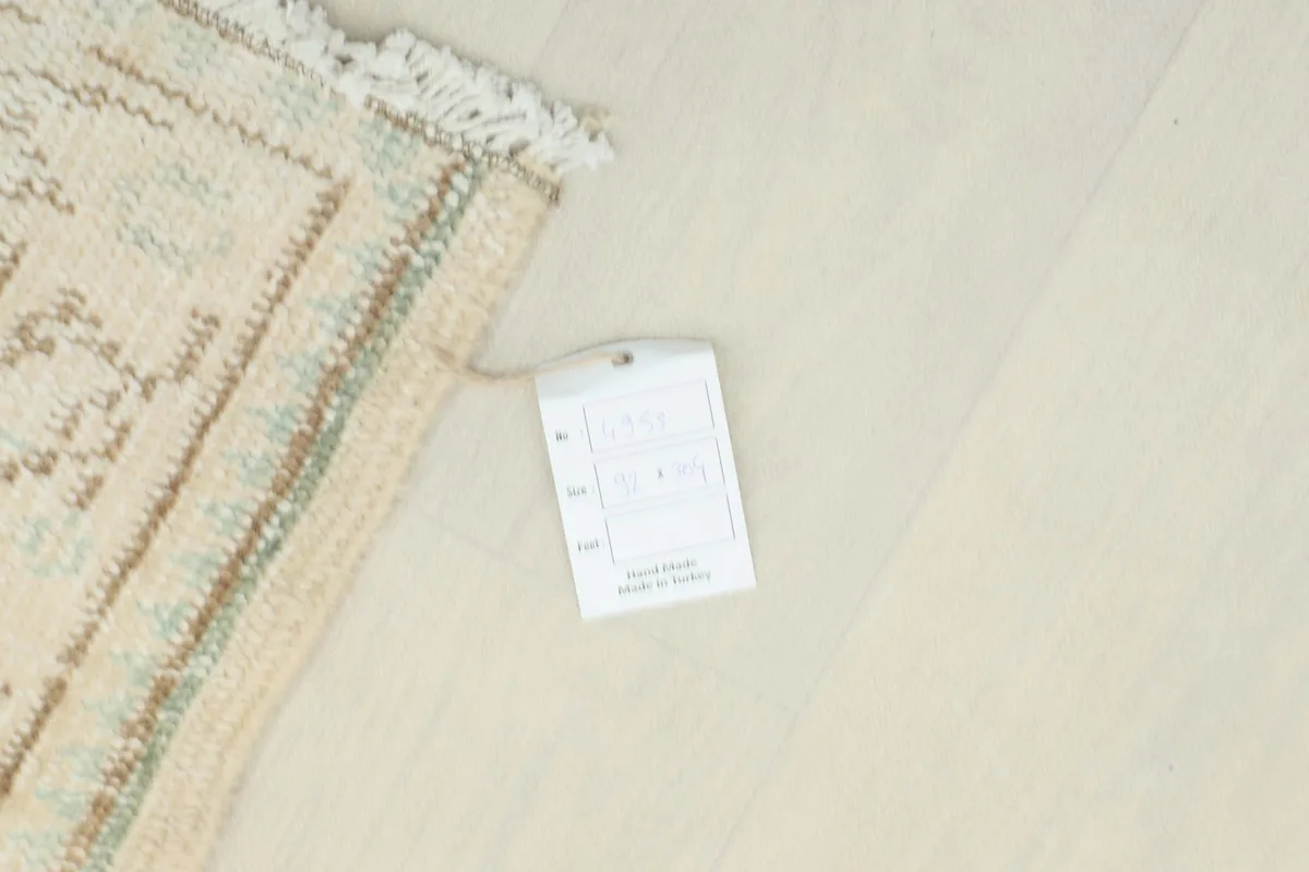 Corner of the cream runner rug with a product tag, indicating its origin from Anatolia, Turkey.