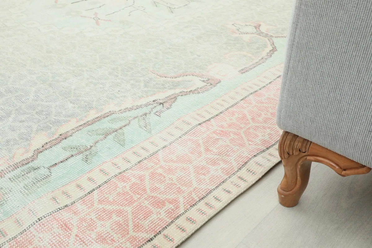 Detail of the rug's edge near a couch leg, highlighting the border and pile